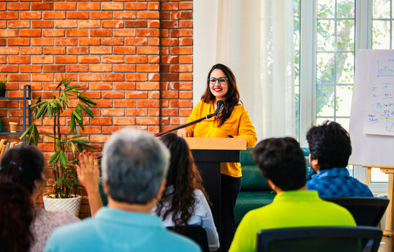 Indian Asian Confident life coach addressing entrepreneurs at a business event with a microphone