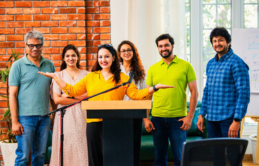 Indian Confident startup leader delivers speech at business conference while her team claps behind