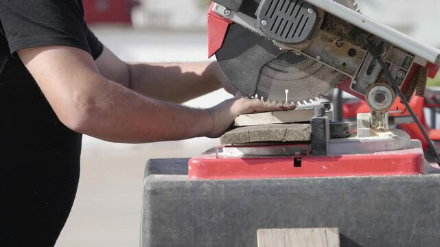 Carpenter creates with precision, cutting wooden boards on a table saw in an open-air workshop