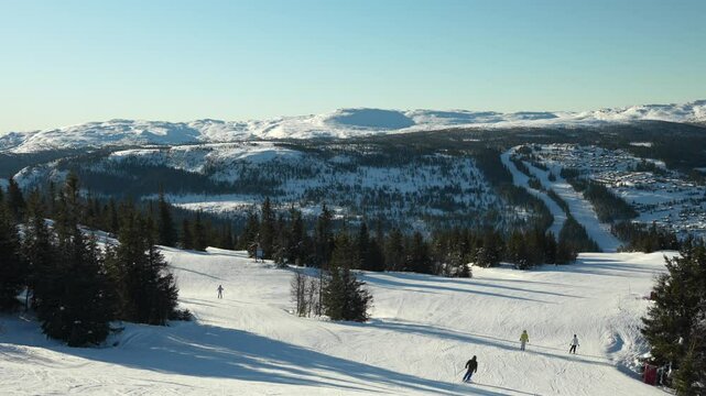 People on easy ski slope in Norway. Sunny conditions at idyllic winter resort
