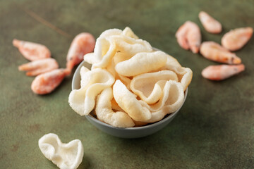 Prawn chips in bowl on green background
