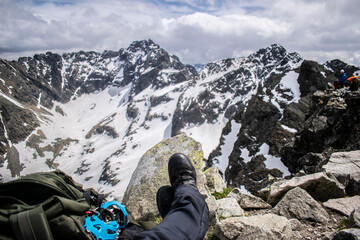 a tourist resting on the top of a snowy mountain. visible mountaineering equipment and snowy mountain peaks