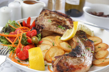Pork chop with rib bone served with potato and green salad	