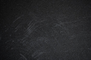 Dark textured surface featuring chalk board residue and scratches, showcasing signs of wear and age, creating a gritty, abstract background