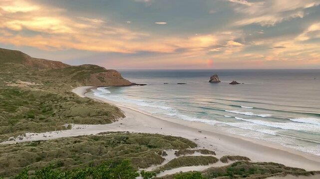 Stunning golden sunset over sandy shore and gentle waves at Sandfly Bay with peaceful coastal beauty and tranquil evening sky, Otago Peninsula, South Island, New Zealand.