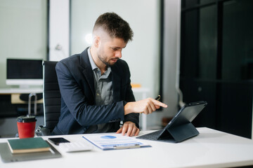 Fototapeta premium Professional businessman working at office with laptop, tablet, and notes. Perfect for business, finance, accounting