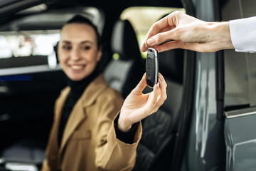 A close-up of the customer receiving the car keys from the dealer in a showroom. Concept an...