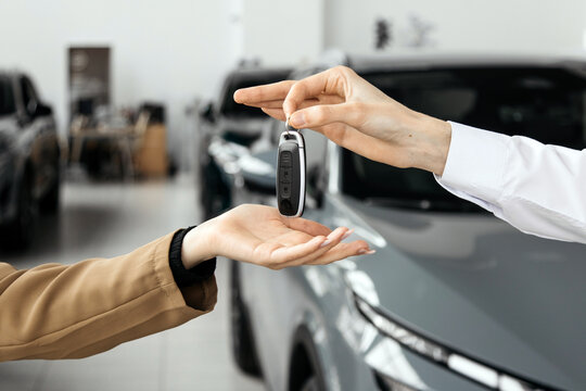 A close-up of the customer receiving the car keys from the dealer in a showroom. Concept an effortless car buying experience, highlighting professionalism and satisfaction in a luxury dealership.