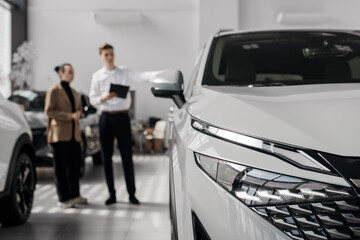 A car dealer in a modern car dealership advises a customer on buying or leasing a new car. The...