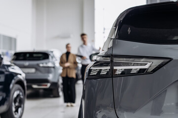 A car dealer in a modern car dealership advises a customer on buying or leasing a new car. The...