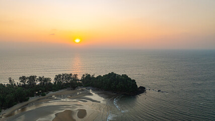 A stunning aerial view of a peaceful coastal island at sunset, with golden hues reflecting on the...