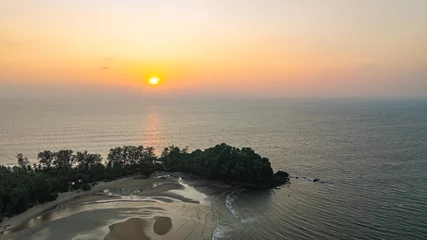 Fotobehang Rustgevend A stunning aerial view of a peaceful coastal island at sunset, with golden hues reflecting on the calm ocean waters. The silhouette of trees and rocky formations adds depth to the tranquil scene.  © Narong Niemhom