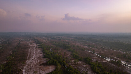 Fototapeta premium A breathtaking view of a savanna landscape at sunrise, with warm hues of orange and pink illuminating the sky. A solitary tree stands prominently amidst the wilderness at Koh Phra Thong, Phang Nga.