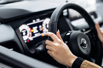 Fototapeta premium A woman's hands rest on the steering wheel of a modern automobile. The confidence and ambition of the concept is reflected in the choice of a new prestige car.