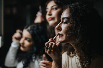 Close-up of young women applying makeup, demonstrating friendship and teamwork as they prepare for an event, showcasing beauty and cooperation.