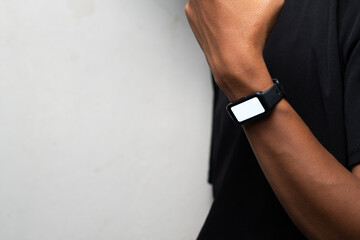 Modern black smartwatch displayed on wrist against light wall, showcasing wearable technology