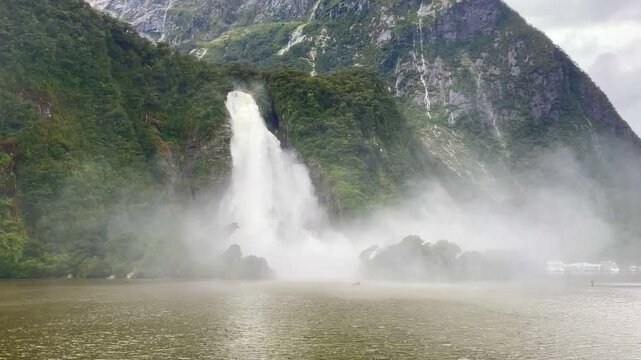 powerful, Lady Bowen Falls falling from high, green, dramatic mountain cliff during a heavy rainfall - Ferry Cruise Through Milford Sound fiord, Fiordland National Park, South Island, New Zealand