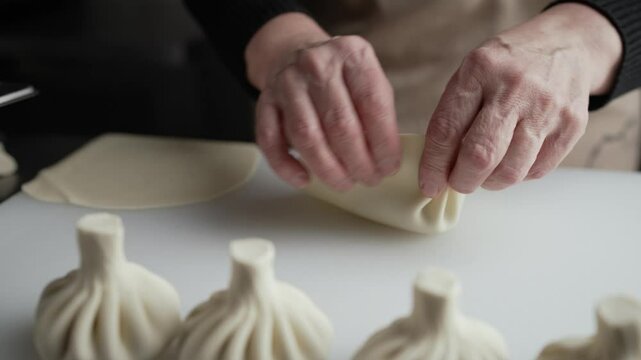 Chef skillfully prepares khinkali, a traditional georgian dumpling, demonstrating the intricate process of filling and pleating the dough