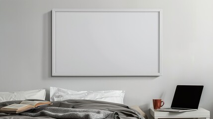 A white rectangular frame hanging in a bedroom above a nightstand with a cup, a laptop, and an open book.  HD 8K mockup wallpaper Photographic Image
