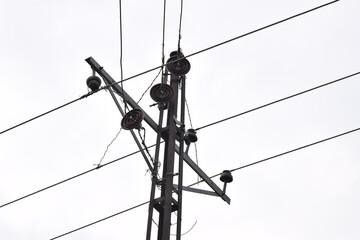 concrete electric pole with four wires running across, isolated against a bright blue clear sky,...