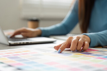 Color Selection and Digital Design. A designer choosing from a palette while working on a laptop.