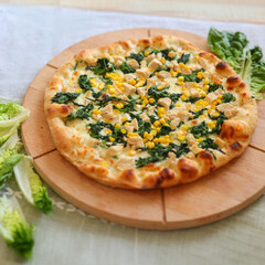 top view of a freshly baked pizza with spinach, chicken and corn, perfectly cooked edges.