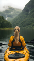 Blonde woman kayaking on tranquil lake surrounded by green mountains and cloudy sky
