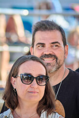 Stylish couple dressed in bright colors and chic accessories, standing closely outdoors. A modern and eye-catching portrait with soft-focus details.