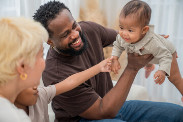 Family playing and bonding at home during a joyful moment with a baby in a cozy living room