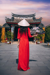 A woman in a traditional Vietnamese dress on the background of an Asian temple in Hoi An