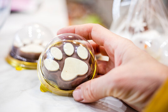 holding a chocolate paw print cookie in her hand