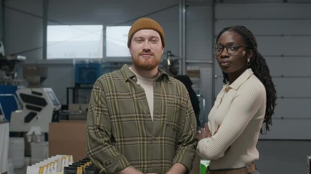 Slow motion portrait shot of two professional and self-confident roasters posing for camera, standing in coffee roasting plant
