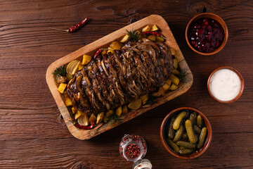 Roasted whole pork neck. Stuffed with onion slices. Served with baked potatoes.