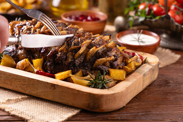 Roasted whole pork neck. Stuffed with onion slices. Served with baked potatoes.