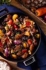 Traditional Asian sweet and sour pork with paprika and sesame. Prepared in a wok.
