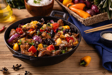 Traditional Asian sweet and sour pork with paprika and sesame. Prepared in a wok.