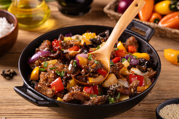 Traditional Asian sweet and sour pork with paprika and sesame. Prepared in a wok.