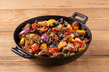 Traditional Asian sweet and sour pork with paprika and sesame. Prepared in a wok.