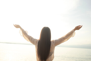 meditative woman in the sea, hands raised to the sky