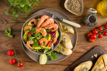 Spring salad with shrimp, mango and avocado. Served in a bowl, with croutons, sprinkled with roasted sunflower seeds.