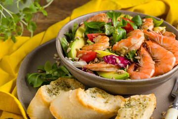 Spring salad with shrimp, mango and avocado. Served in a bowl, with croutons, sprinkled with roasted sunflower seeds.