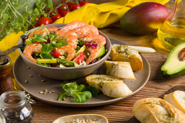 Spring salad with shrimp, mango and avocado. Served in a bowl, with croutons, sprinkled with roasted sunflower seeds.