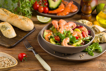 Spring salad with shrimp, mango and avocado. Served in a bowl, with croutons, sprinkled with roasted sunflower seeds.