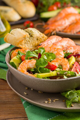 Spring salad with shrimp, mango and avocado. Served in a bowl, with croutons, sprinkled with roasted sunflower seeds.