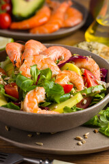 Spring salad with shrimp, mango and avocado. Served in a bowl, with croutons, sprinkled with roasted sunflower seeds.