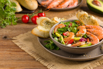 Spring salad with shrimp, mango and avocado. Served in a bowl, with croutons, sprinkled with roasted sunflower seeds.