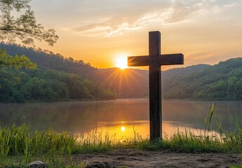 Standing Cross Overlooking Peaceful Lake at Sunrise with Mountains Backdrop