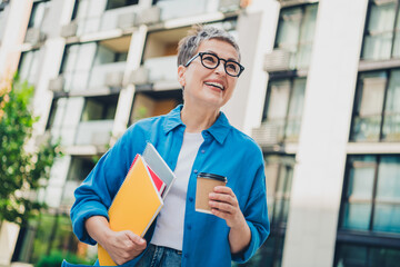 Portrait of pretty aged woman hold book coffee think wear blue shirt weekend walk city center...