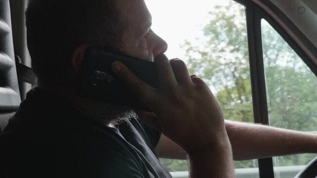 A delivery worker dangerously talks on the phone while driving, showing an irresponsible behavior that can lead to serious consequences.