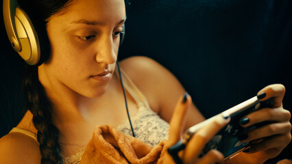 A teenage girl relaxes in a quiet, cozy space, completely absorbed in her phone